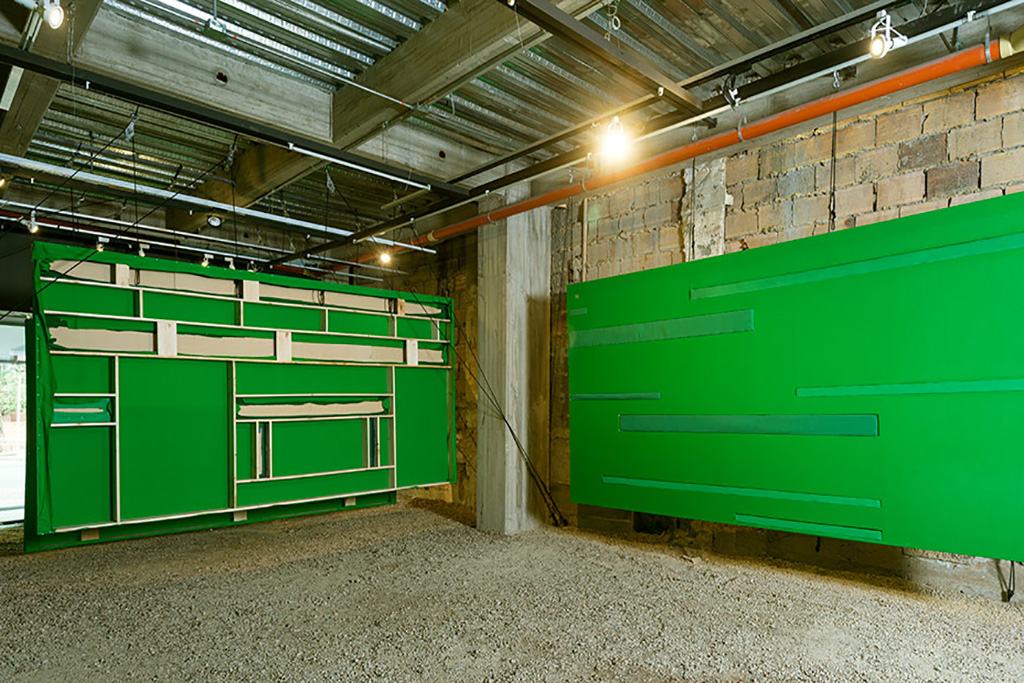 Third floor of Again's intallation showing large scale facades made with green screen and other green fabrics