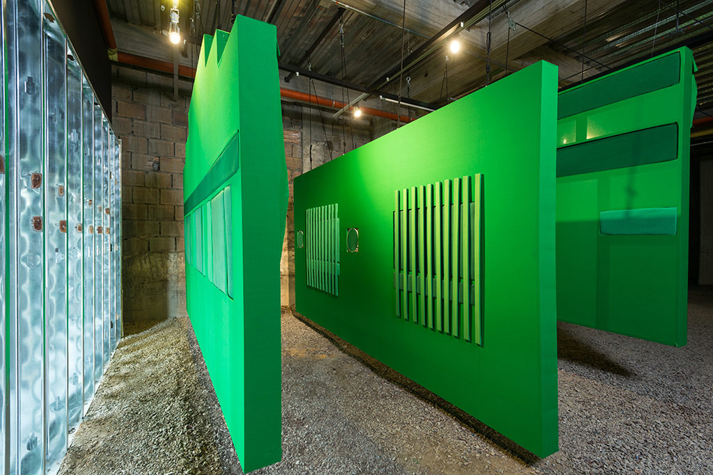 Third floor of Again's intallation showing large scale facades made with green screen and other green fabrics