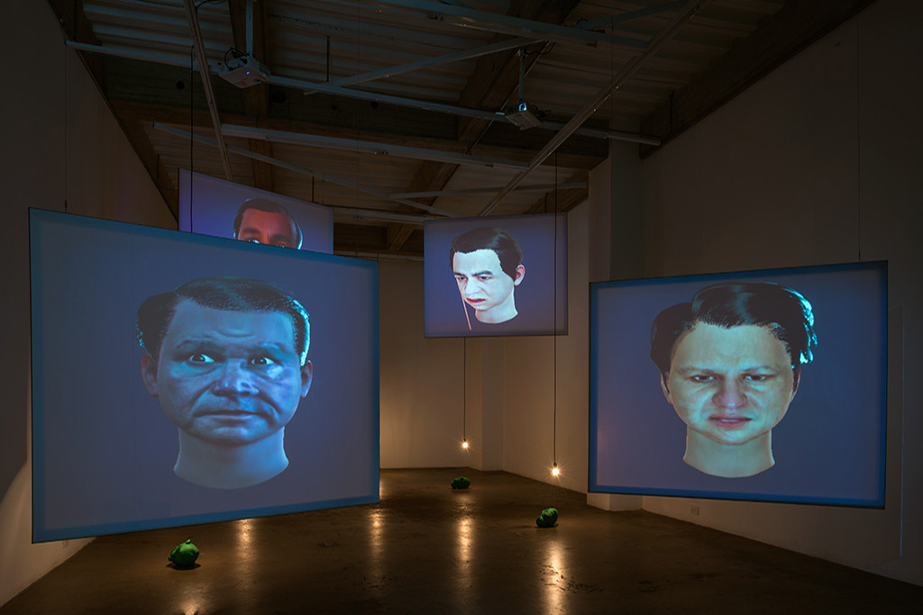 second floor of Again exhibition, four screens show 3d generated faces of corrupt polititians and green screen heads on the floor