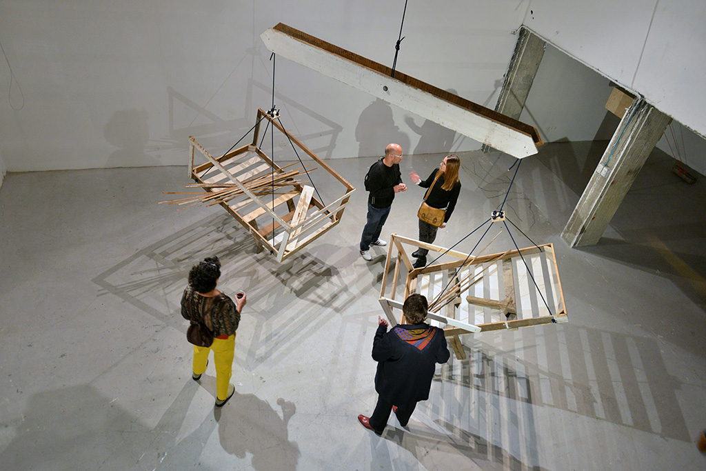 Actors interacting with visitors in front of the scale sculpture at the exhibition opening for Machine