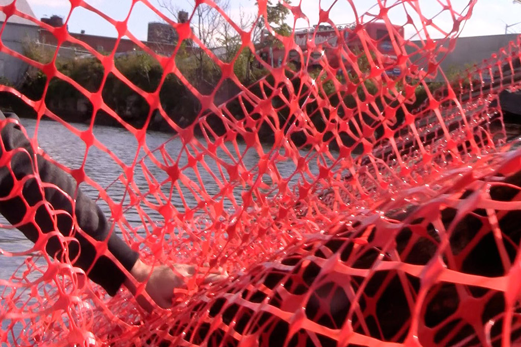 Orange fencing being placed on the sunken dock at the Gowanus canal in Brooklyn